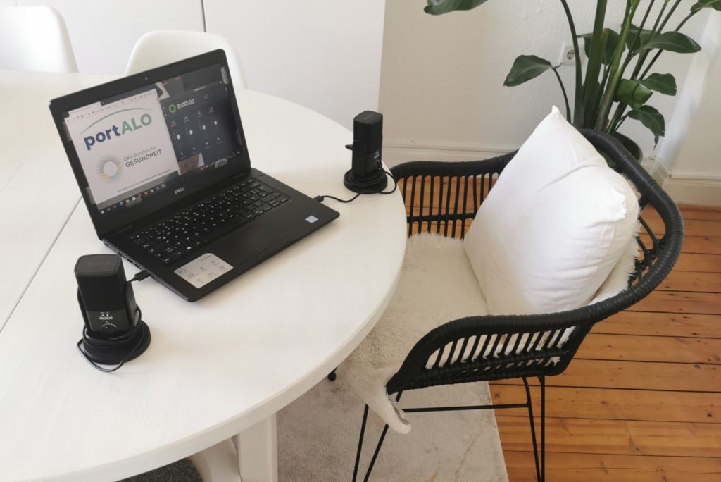 EIn Tisch und ein Stuhl. Auf dem Tisch steht ein Laptop und ein großes Mikrofon..